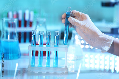 Scientist hand holding test tube in laboratory on blurred background