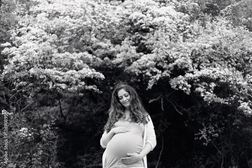 Beautiful pregnant women holding her belly. Summer nature.