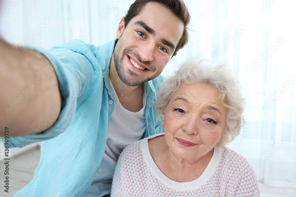 Young man taking selfie with grandmother at home