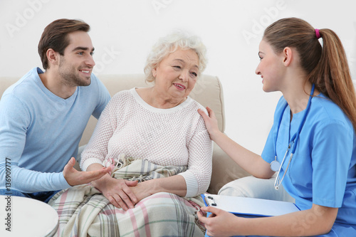 Nurse talking with grandmother and her grandson indoors © Africa Studio