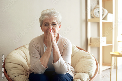 Praying elderly woman sitti...