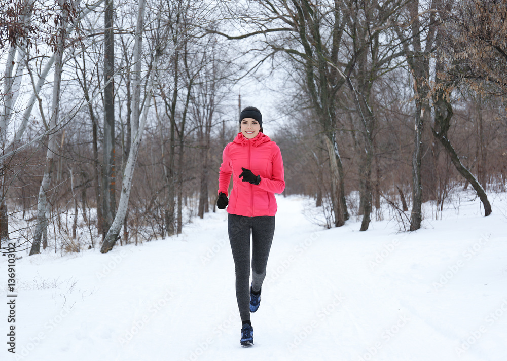 Young beautiful woman jogging in winter park