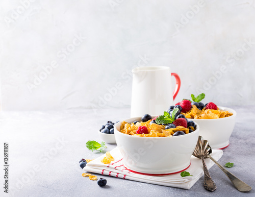 Healthy breakfast with corn flakes, berries and milk on light gray background. Copy space. photo
