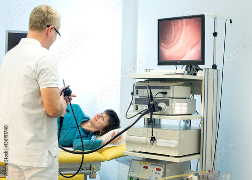 Arzt in der Gastroenterologie mit Gastroskop in der Hand erklärt Patientin die Untersuchung photo