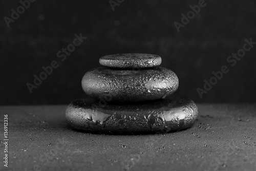 spa concept of zen basalt stones with water drops on black backg