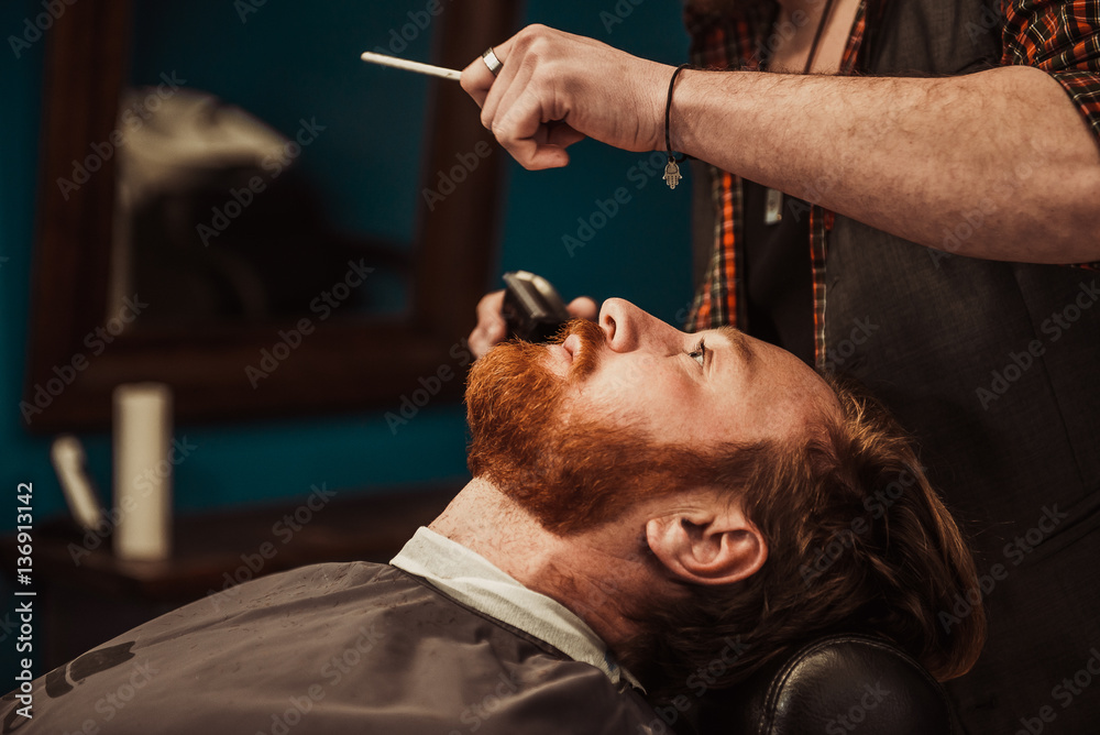 Fototapeta premium Professional Master hairdresser cuts client beard.