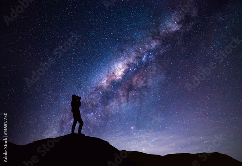 Milky Way landscape. Silhouette of Happy woman taking a bright star photograph.