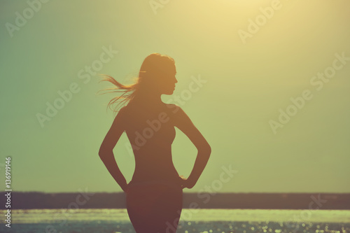 Silhouette of a beautiful, slim girl on a background of a sunset on the beach.