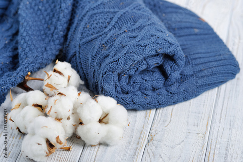 Fototapeta Naklejka Na Ścianę i Meble -  Still life with blue trendy winter knitted sweater and delicate white flowers of cottons