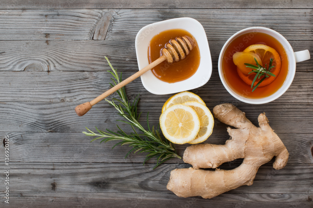 Ginger,lemon,rosemary,tea and honey on grey wooden background.Top view. Ginger,lemon,rosemary,tea and honey on grey wooden background.Top view.