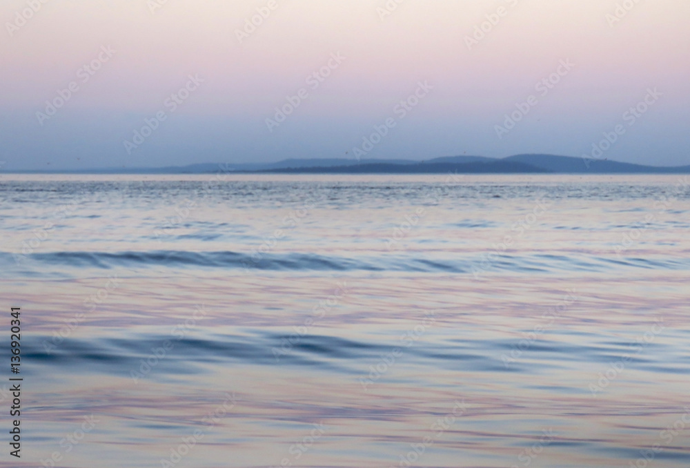 Waves with mountains lake landscape at dawn or dusk pink and blue background
