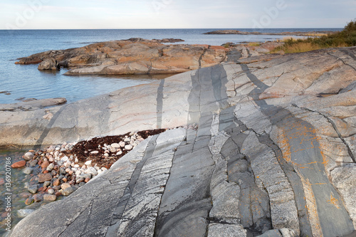 Strange dark geological stripes in the rock by the coastline photo