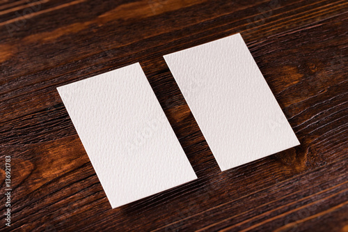 Closeup mockup of two blank vertical business cards at brown woo