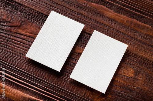 Closeup mockup of two blank vertical business cards at brown woo