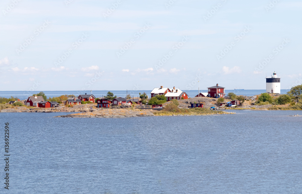Lighthouse and some small red cottages on a tiny island in the s