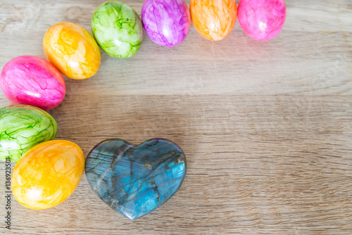 Herz aus Falkenauge Edelstein auf einem Holzbrett mit bunten Ostereier photo