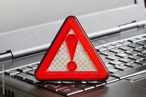 Caution sign on black laptop computer virus detected alert hacking piracy concept 