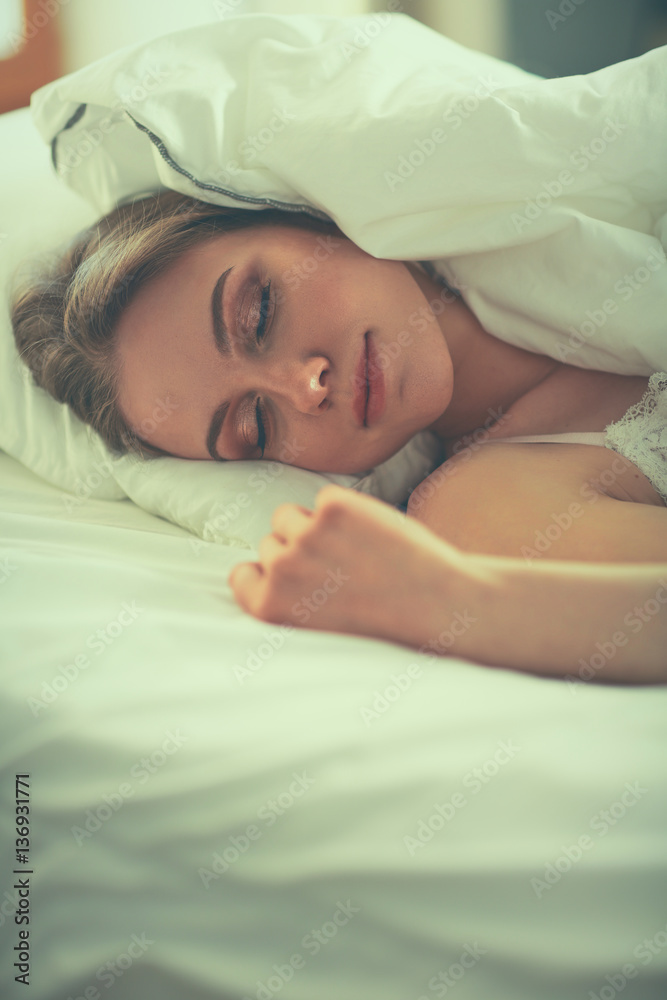 Pretty woman lying down on her bed at home