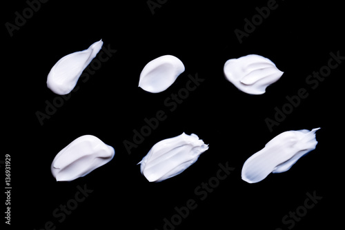 Collection of various strokes of a white beauty cream on black b