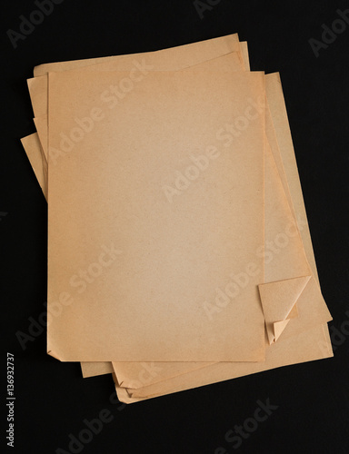 old craft paper sheets pile isolated on black background