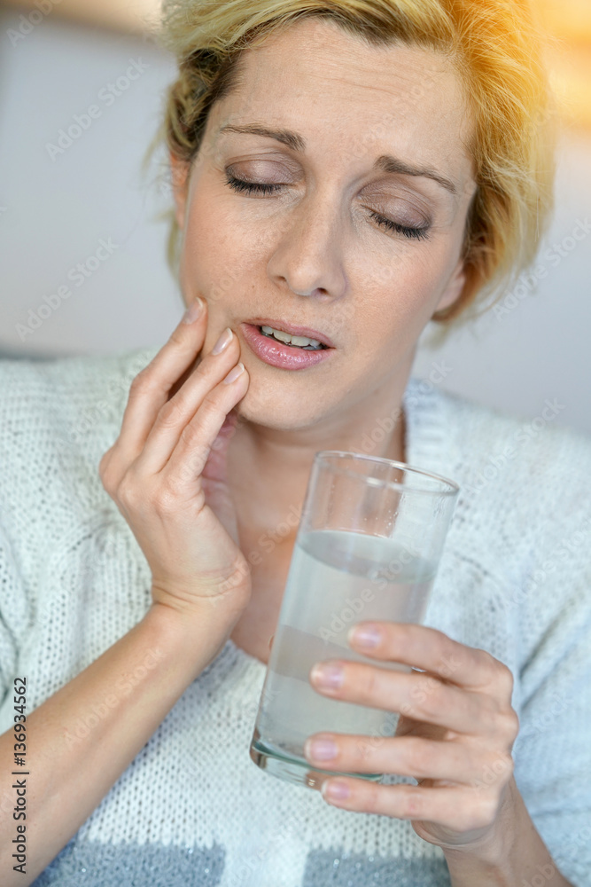 Middle-aged woman taking tylenol to ease toothache Middle-aged woman taking tylenol to ease toothache