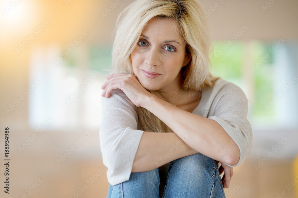 Blond woman with blue eyes sitting on table Blond woman with blue eyes sitting on table