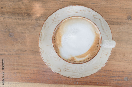 White cup of coffee on wooden table in the coffee shop.