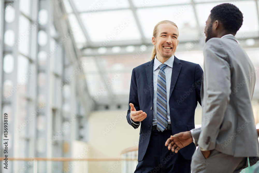 Happy businessman talking to his African colleague Happy businessman talking to his African colleague