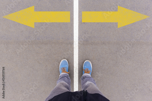 Tableau sur toile Arrows on asphalt ground, feet and shoes on floor