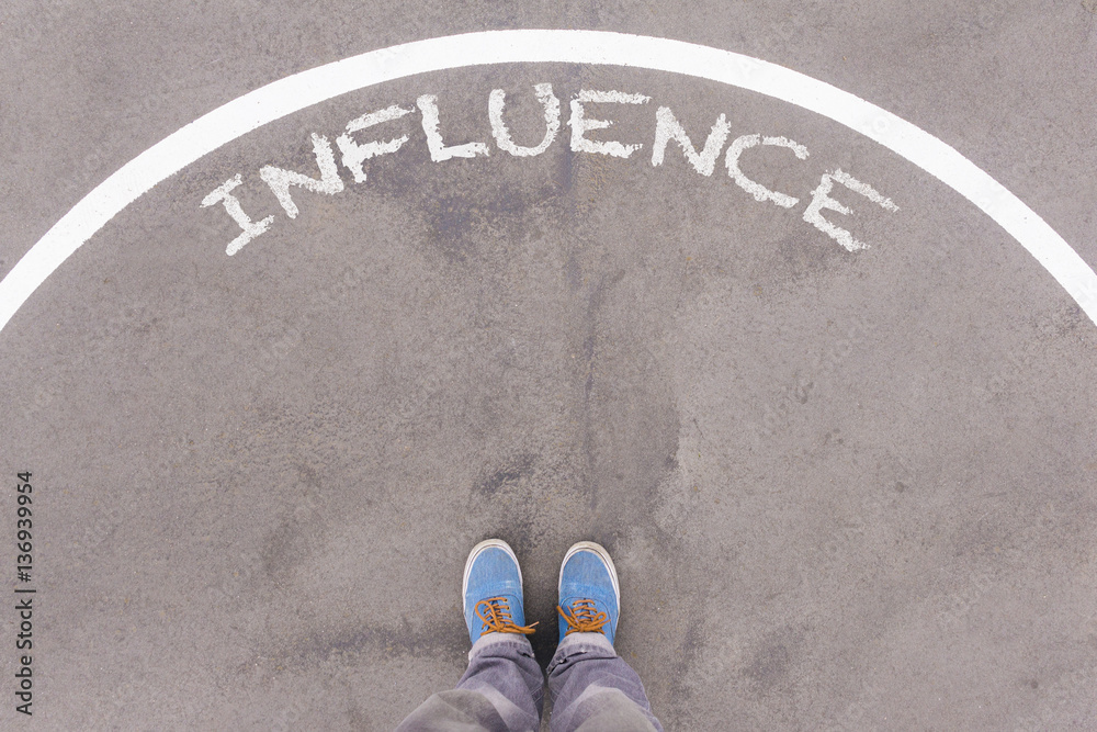 Influence text on asphalt ground, feet and shoes on floor