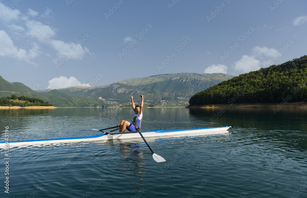 Naklejka premium The young sportsman is rowing on the racing kayak