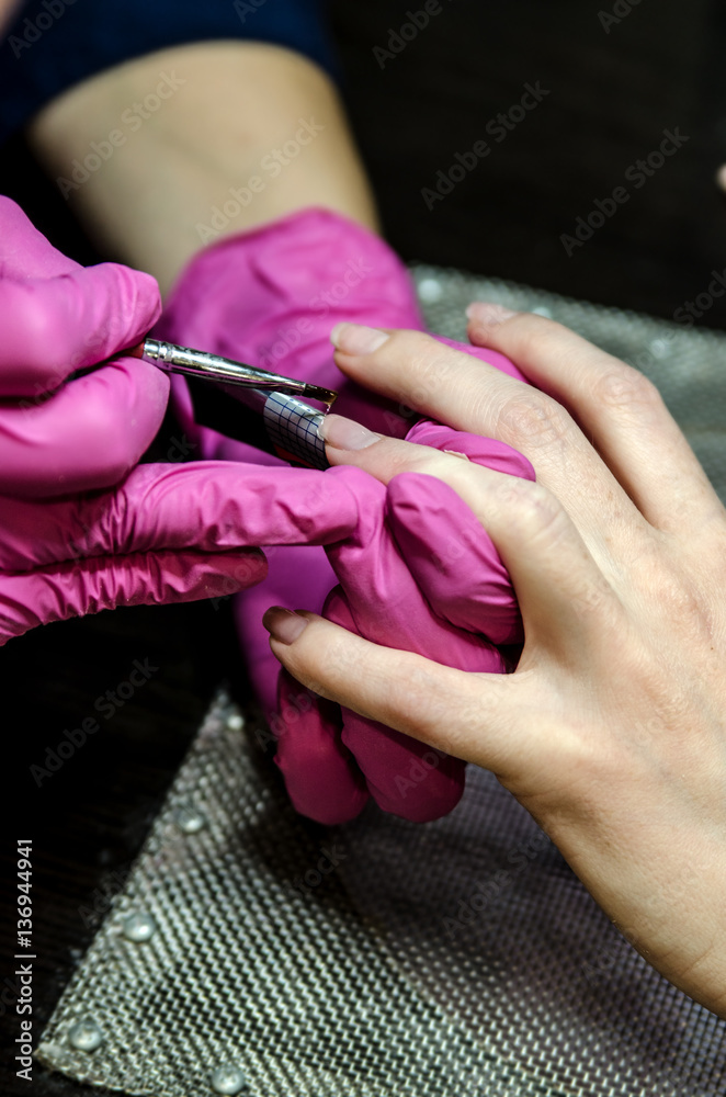 Obraz premium Application of gel on the nail to lengthen the nail plate. Under the nail attached special sticker to adjust the length of the application and the required amount of gel.