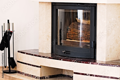 Firewood cut in a marble surround fireplace. Modern interior design