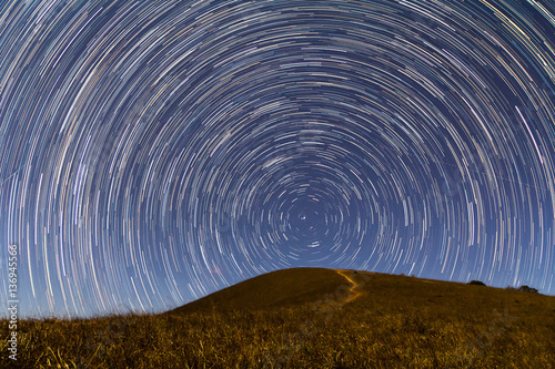Long exposure image showing star trails over the hill
