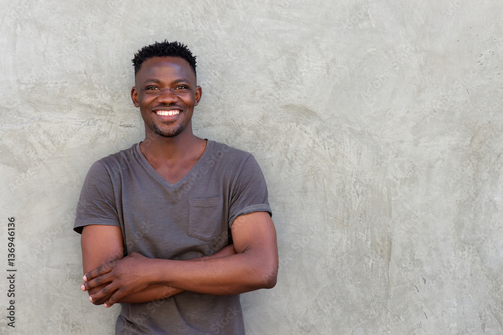 happy african man smiling with arms crossed by wall happy african man smiling with arms crossed by wall
