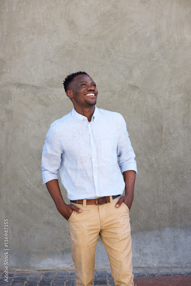 modern young black man smiling with hands in pockets modern young black man smiling with hands in pockets