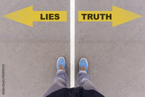 Lies vs truth text arrows on asphalt ground, feet and shoes on f photo