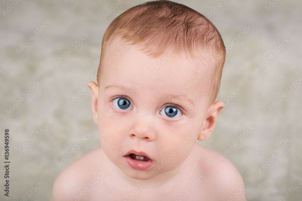 Cute white baby boy with large blue eyes looking up at camera with his mouth open as if intrigued by the camera. Cute white baby boy with large blue eyes looking up at camera with his mouth open as if intrigued by the camera.