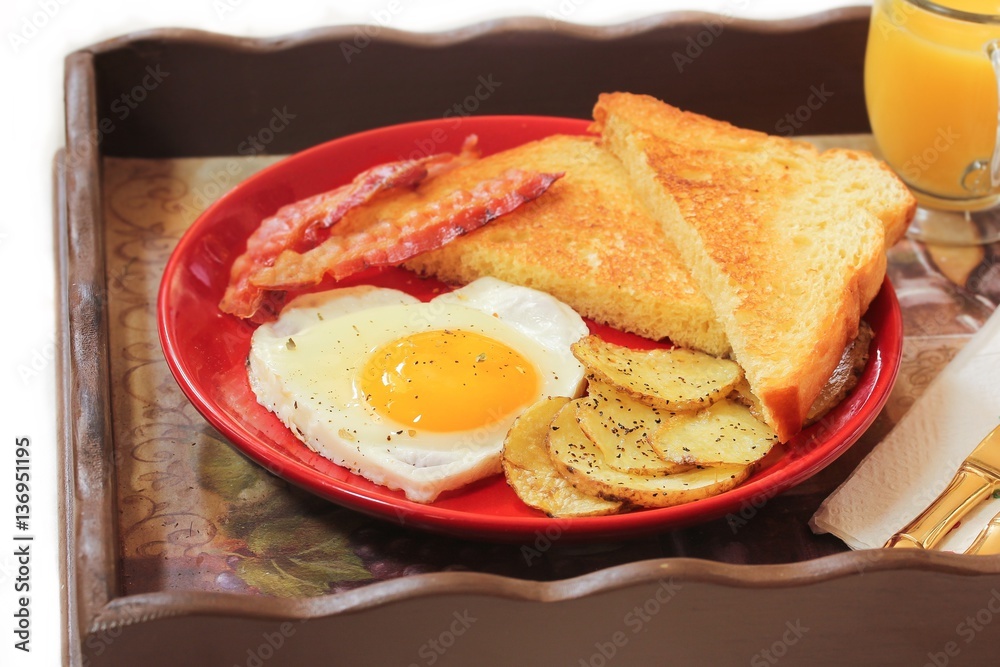 Breakfast in bed with egg heart Bacon bread toast roasted potatoes and orange juice served in wooden tray for Valentine's day Breakfast in bed with egg heart Bacon bread toast roasted potatoes and orange juice served in wooden tray for Valentine's day
