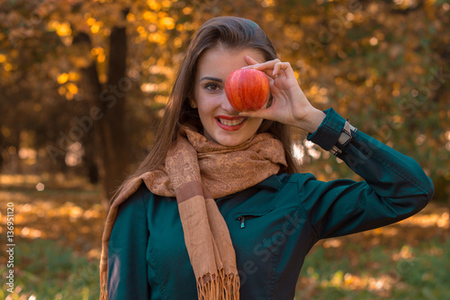 young girl in long scarf keeps Apple near the eyes and smiles