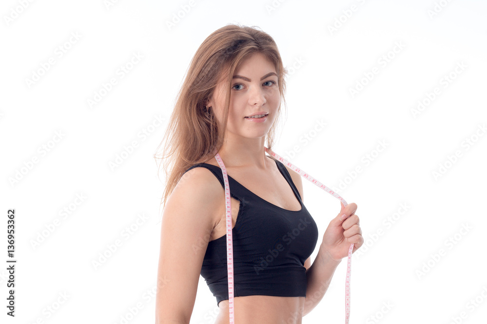 close-up of young sexy athletic girl who is standing sideways and looking directly holds a tape measure close-up of young sexy athletic girl who is standing sideways and looking directly holds a tape measure