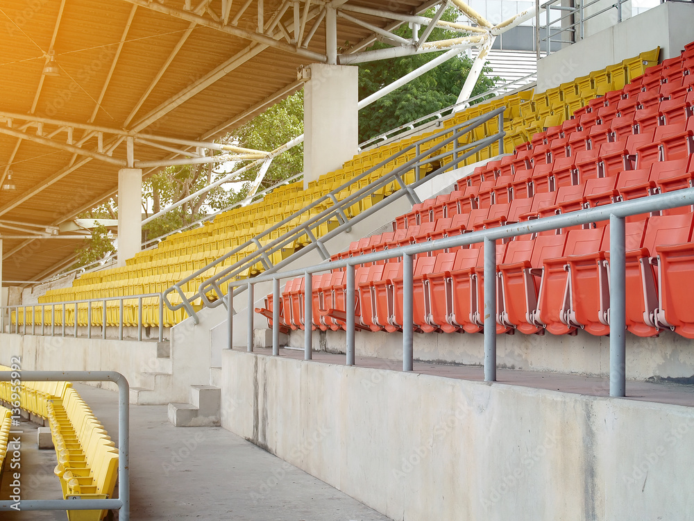 Fototapeta premium row of empty stadium grandstand seats in sport arena with evening sunlight