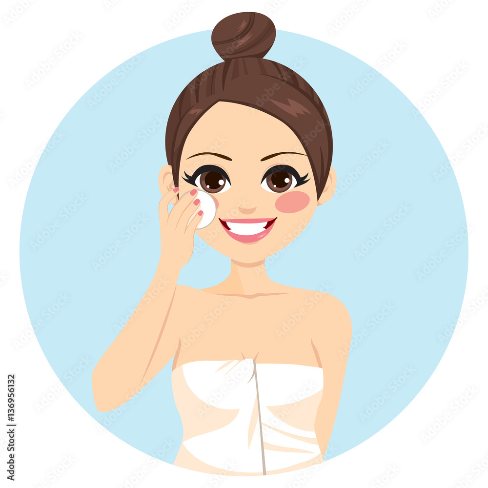 Cute brunette woman with hair bun cleaning face with white cotton pad Cute brunette woman with hair bun cleaning face with white cotton pad