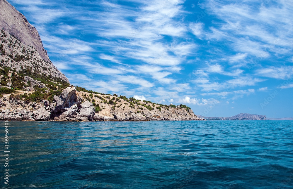 Landscape with sea in the foreground, a mountainous distant shore, blue sky with a pattern of Cirrus clouds. Crimea.
