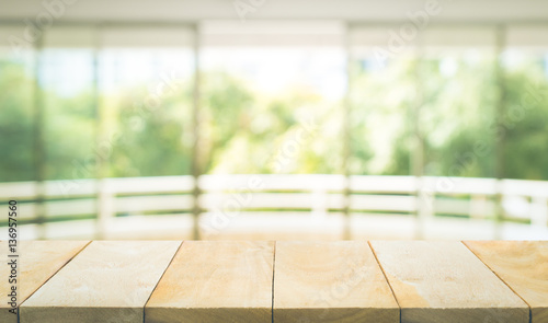 Empty wood table top on blur abstract green garden from window view background.