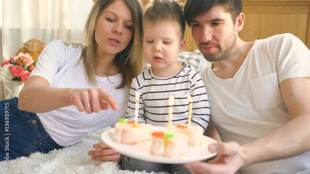 Smiling family celebrating their son birthday together before blowing candles on cake Smiling family celebrating their son birthday together before blowing candles on cake