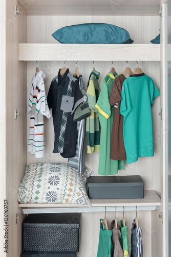 clothes hanging on rail in wooden wardorbe