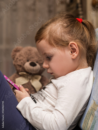 Beautiful kid girl looking at smartphone screen