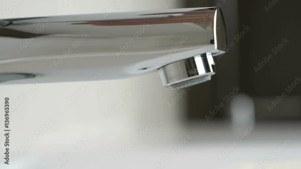 Stylish faucet in bathroom. Flow of water pouring from chrome-plated faucet. Close-up Stylish faucet in bathroom. Flow of water pouring from chrome-plated faucet. Close-up