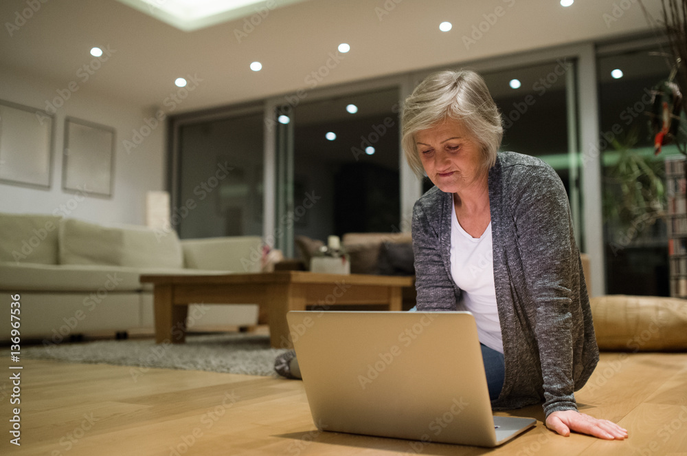 Senior woman sitting on the floor working on laptop Senior woman sitting on the floor working on laptop